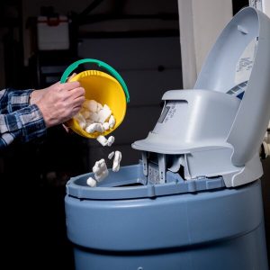 person adding salt to a water softener