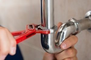 Closeup photo of a plumber tightening a connection on a pipe